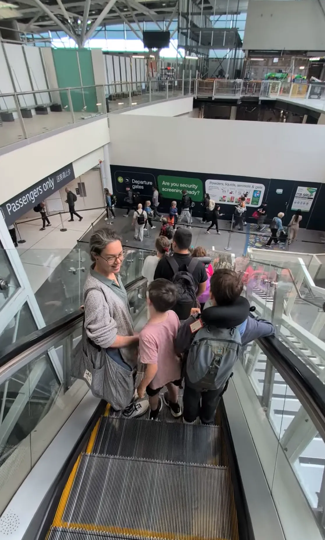 Lyndsie and the kids on the escalator down toward the departure gates and security at Brisbane Airport