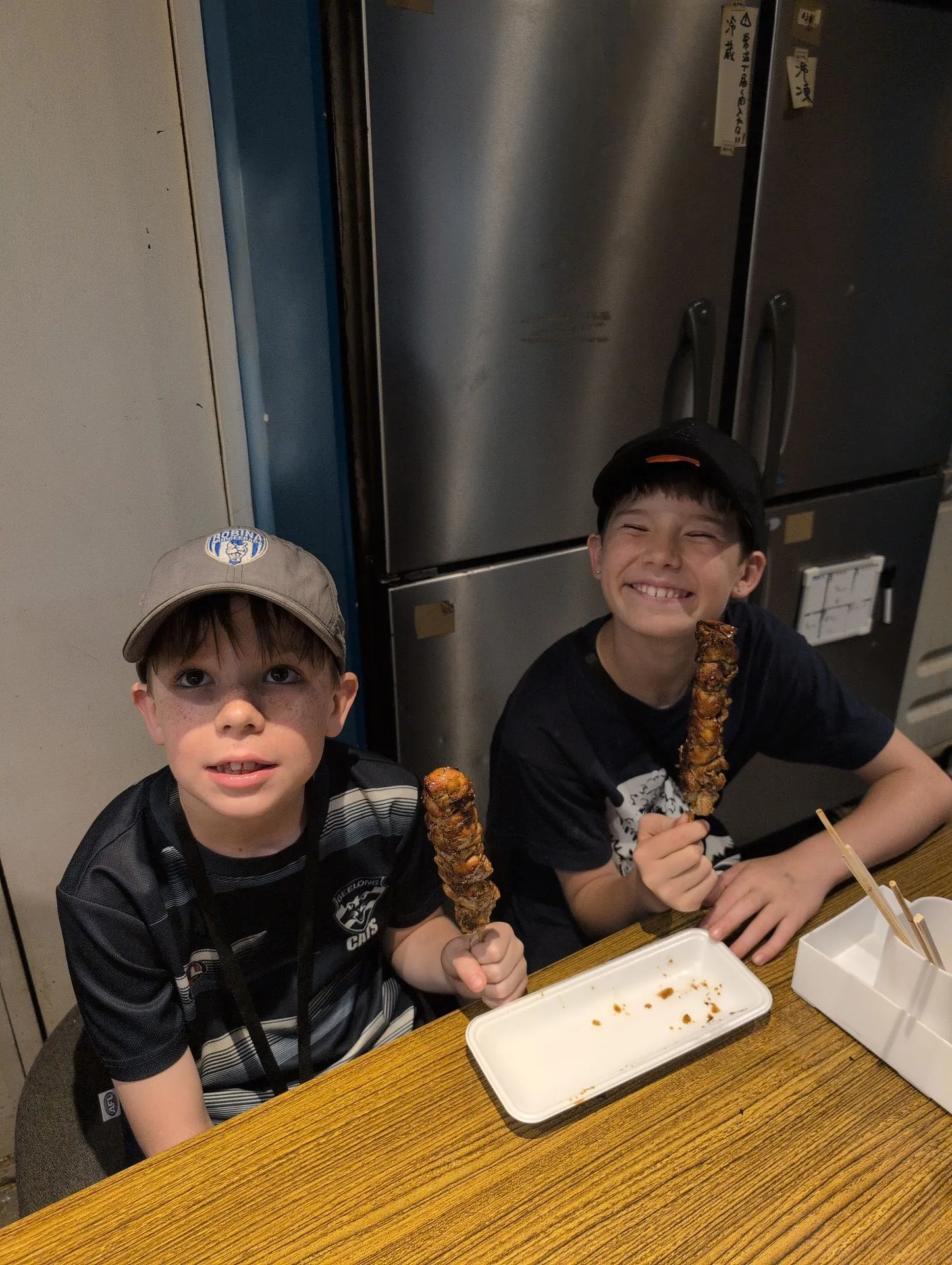Kids holding grilled chicken yakitori skewers near Fushimi Inari, Kyoto