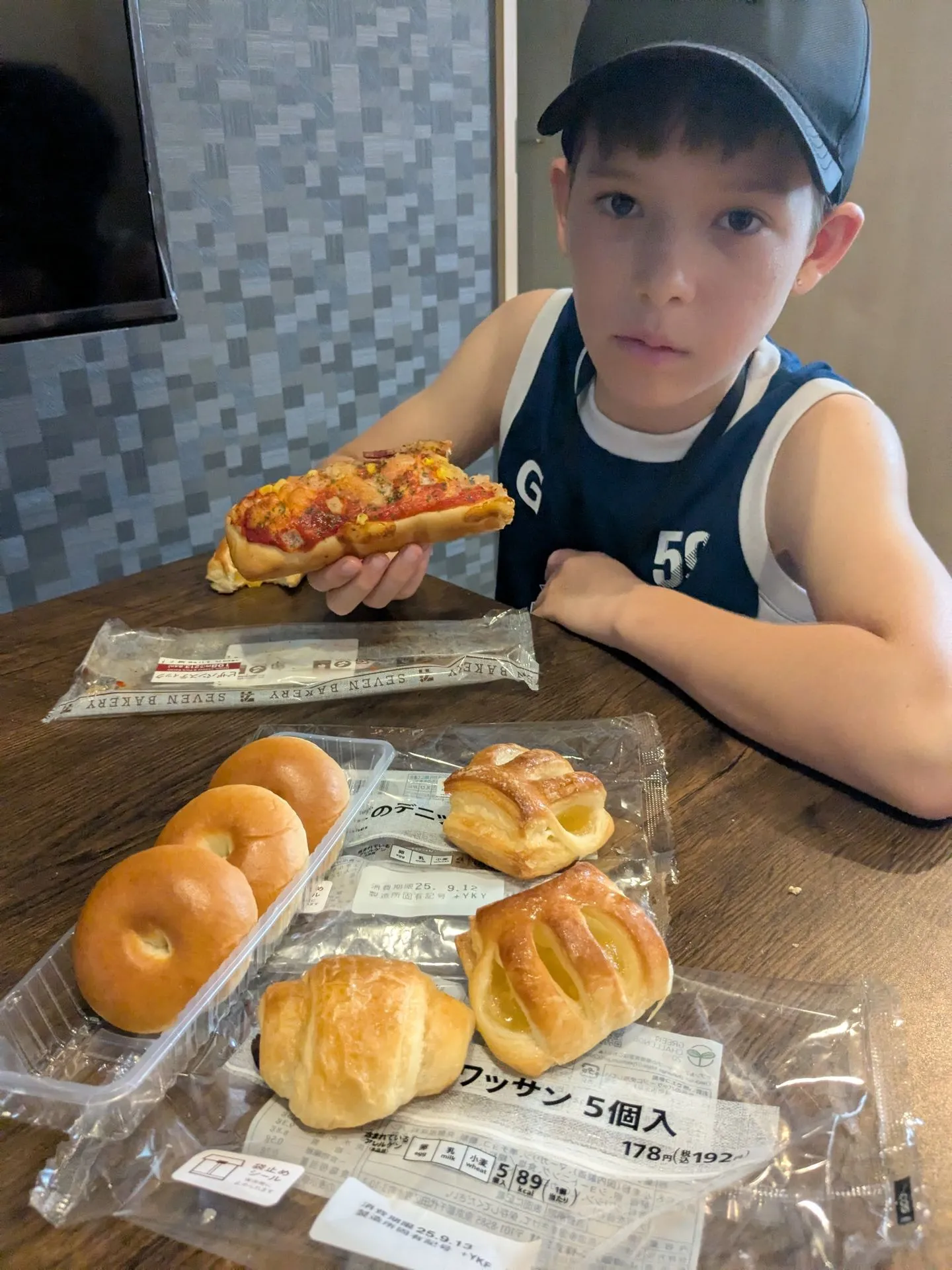A child choosing bread and pastries from a convenience store shelf in Namba, Osaka
