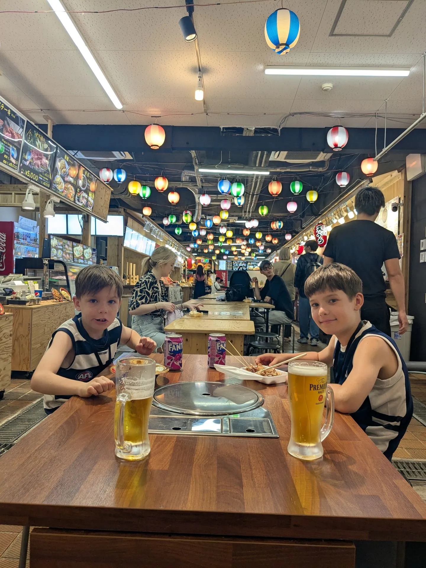 Our boys eating lunch under red paper lanterns at a food hall in Namba, Osaka