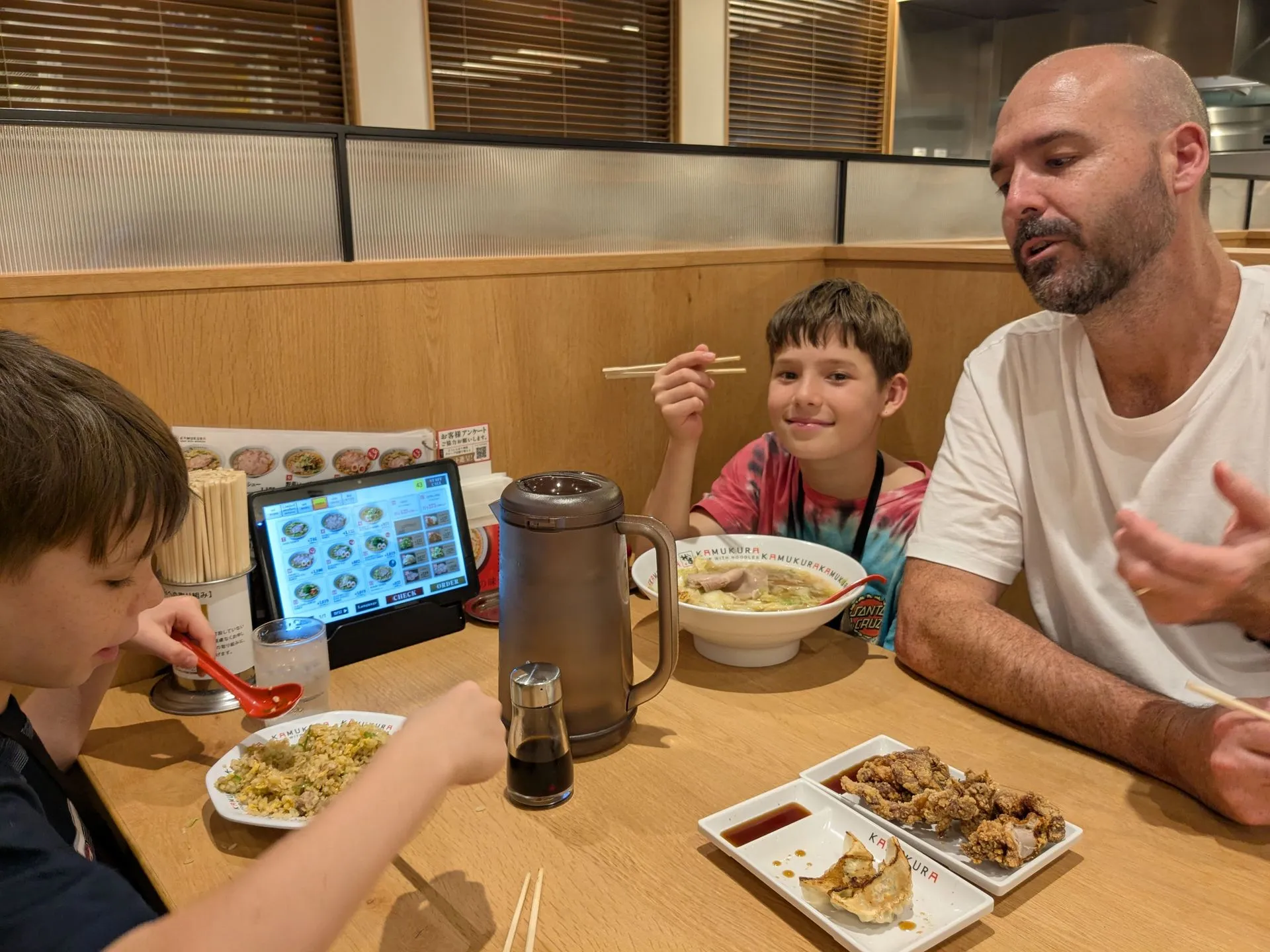 Our family around a table of steaming ramen bowls in a Namba restaurant, Osaka