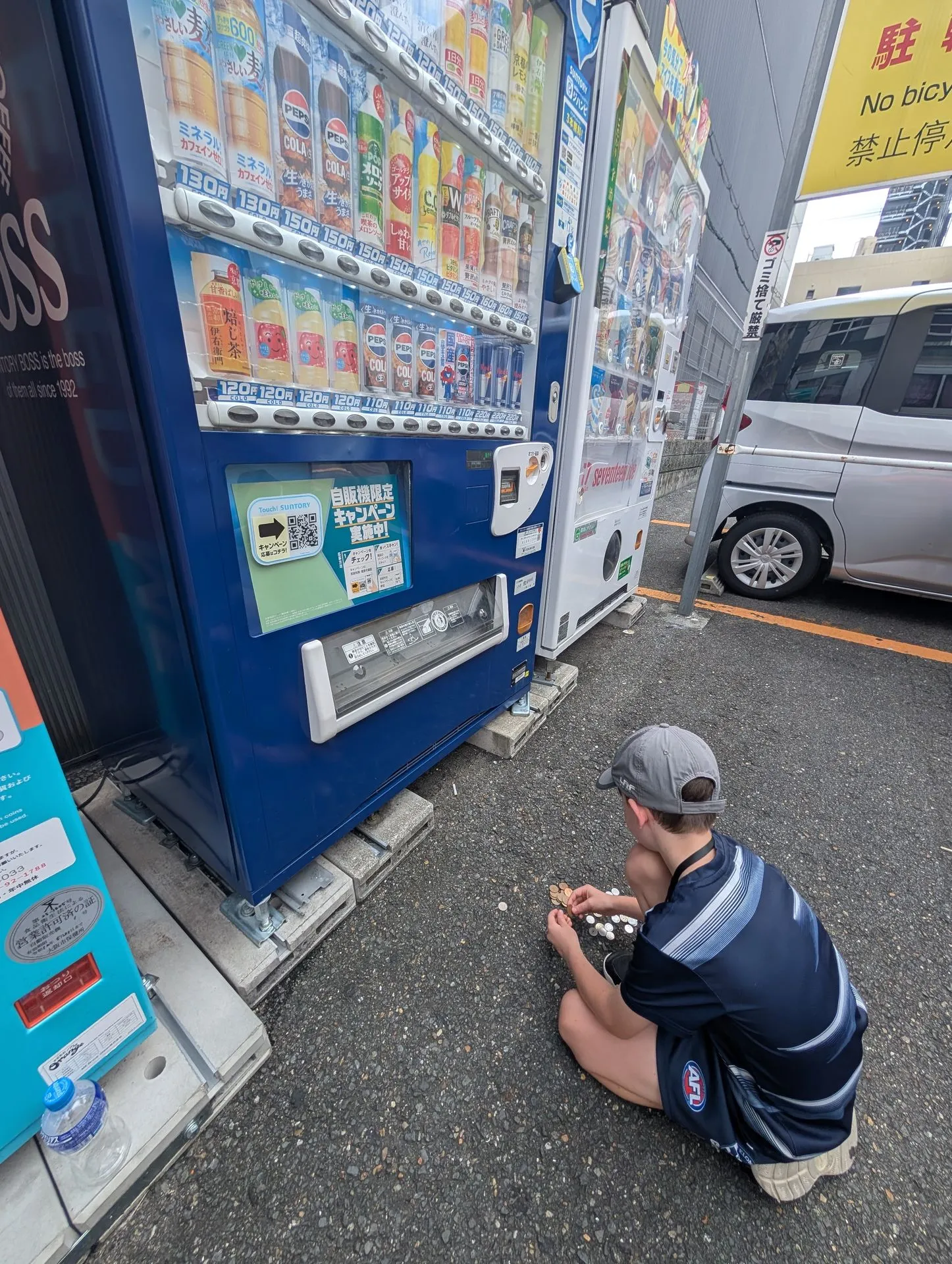 One of the boys buying a drink from a street vending machine in Namba, Osaka, with his IC card