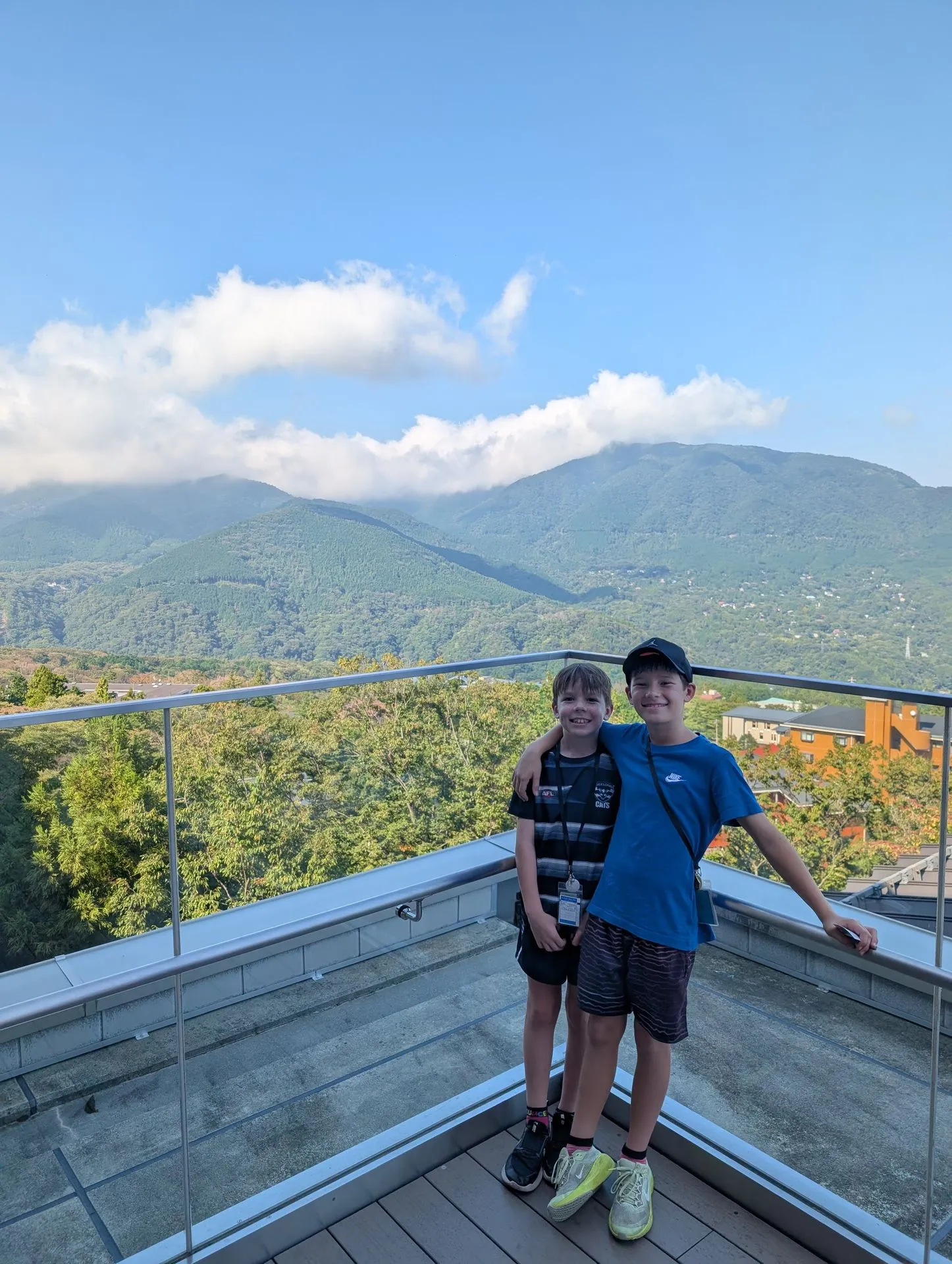 Two boys on a viewing platform along the Hakone Ropeway with mountain views behind them