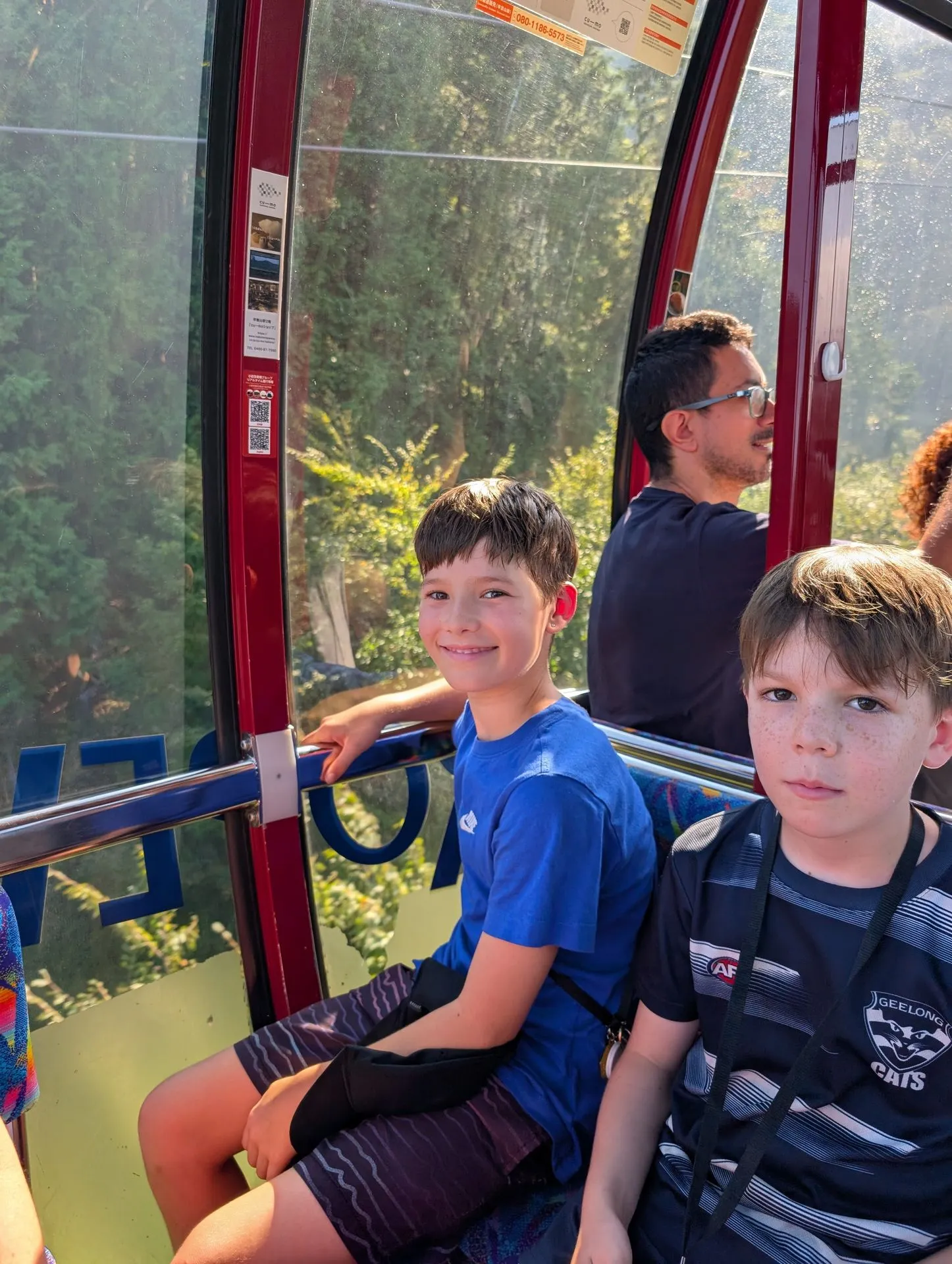 Kids inside a Hakone Ropeway gondola with mountain views through the windows