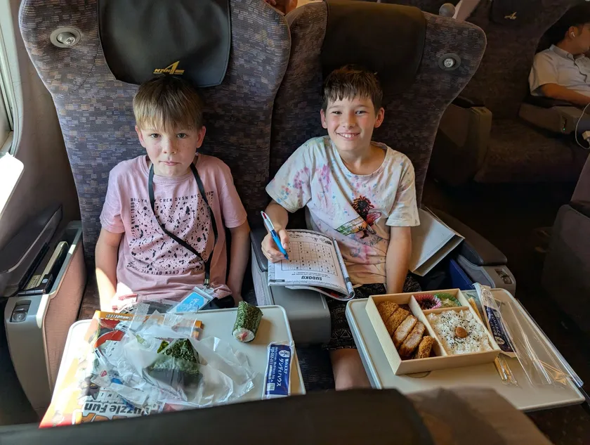 Kids eating ekiben bento boxes in their seats on the shinkansen