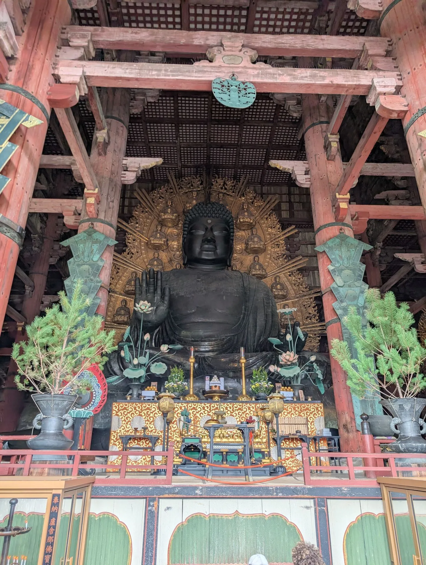 The Great Daibutsu bronze Buddha inside Todai-ji temple, surrounded by golden lotus decorations and red wooden temple pillars