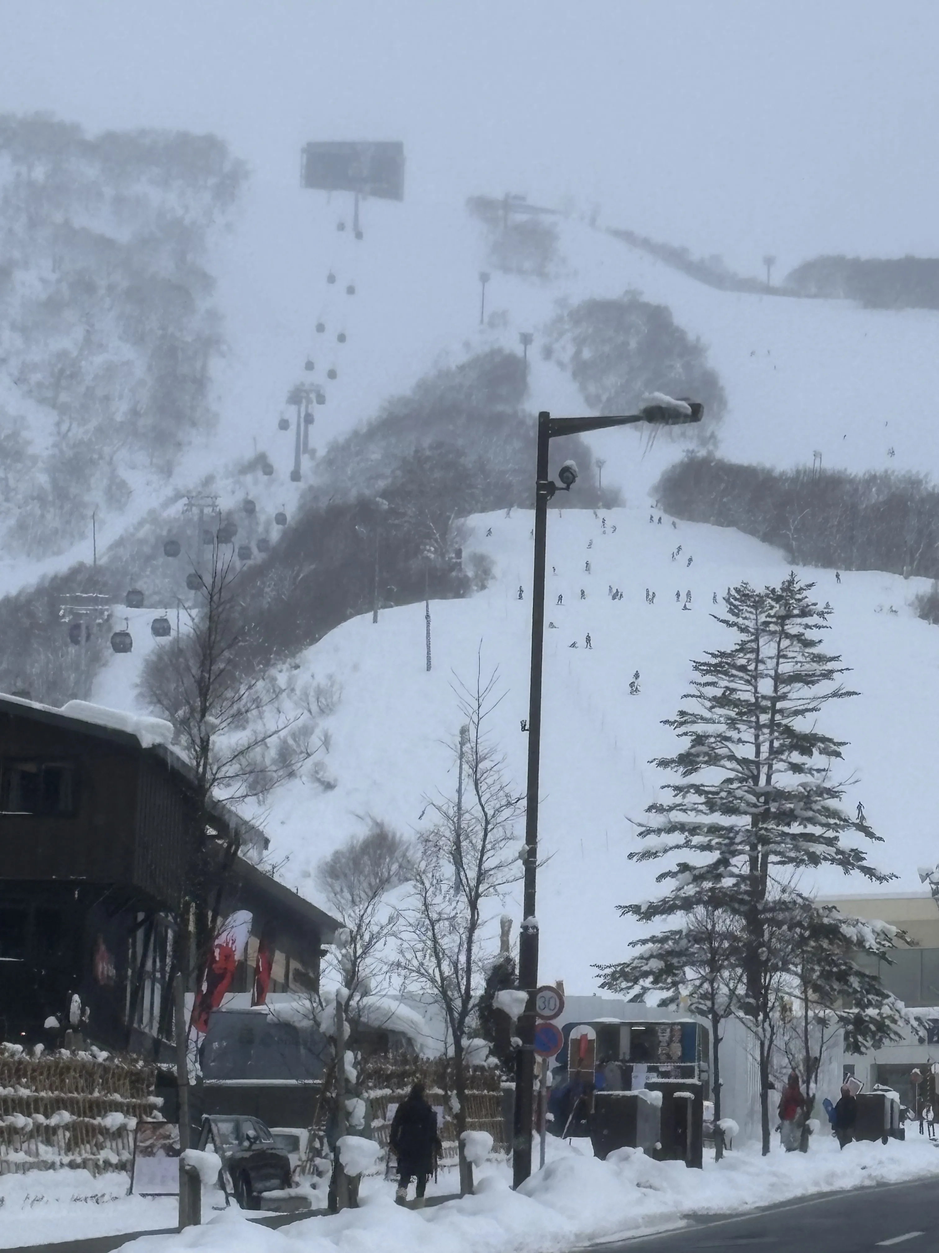 The ski slopes and gondola of Grand Hirafu rising directly above the shops and streets of Hirafu village