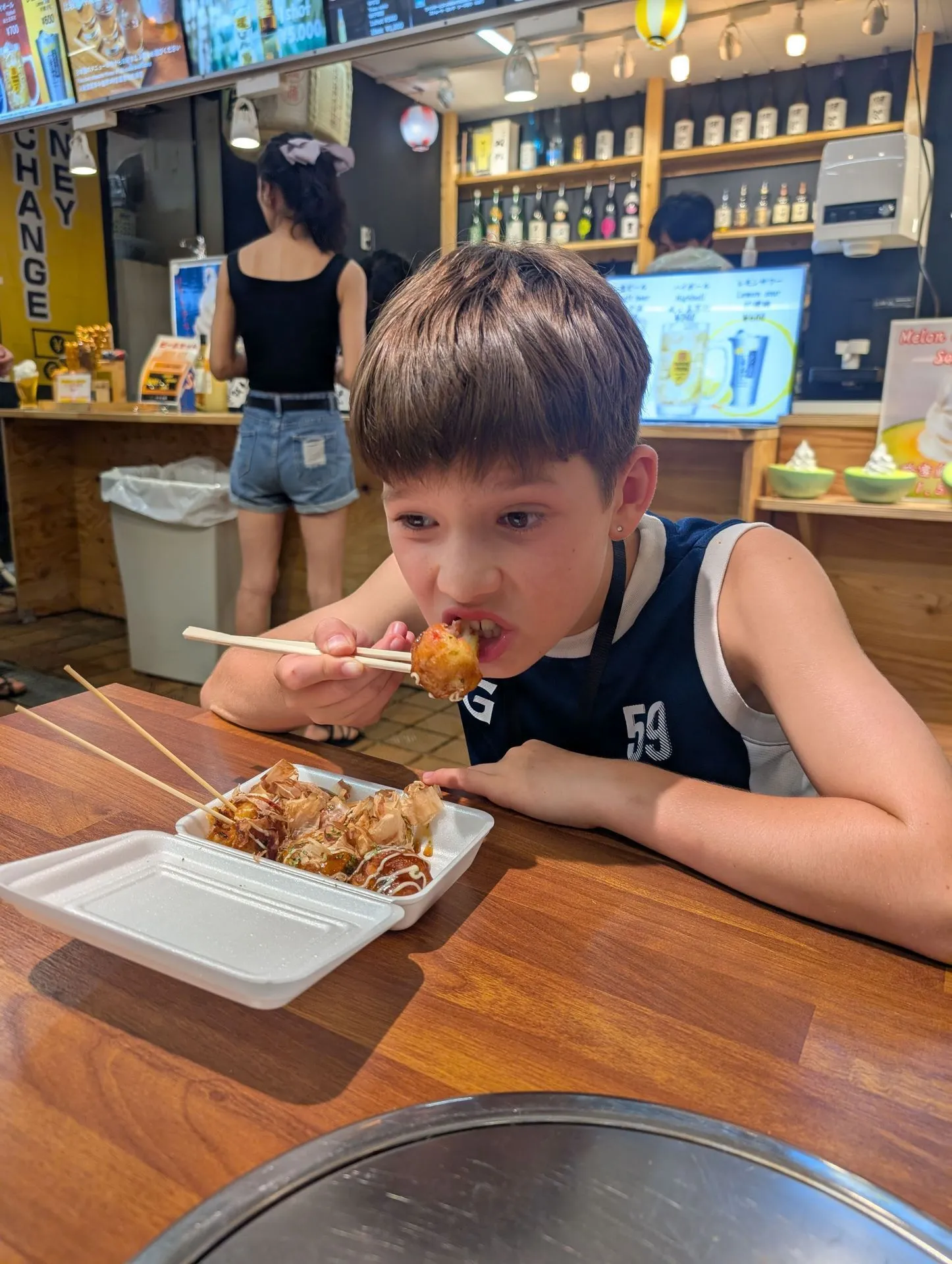 Eating takoyaki octopus balls at a Dotonbori street stall in Osaka