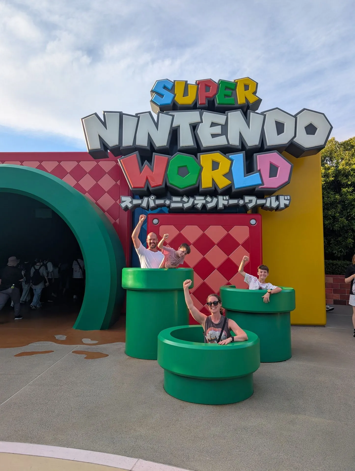 Family posing at the green warp pipe entrance to Super Nintendo World at USJ