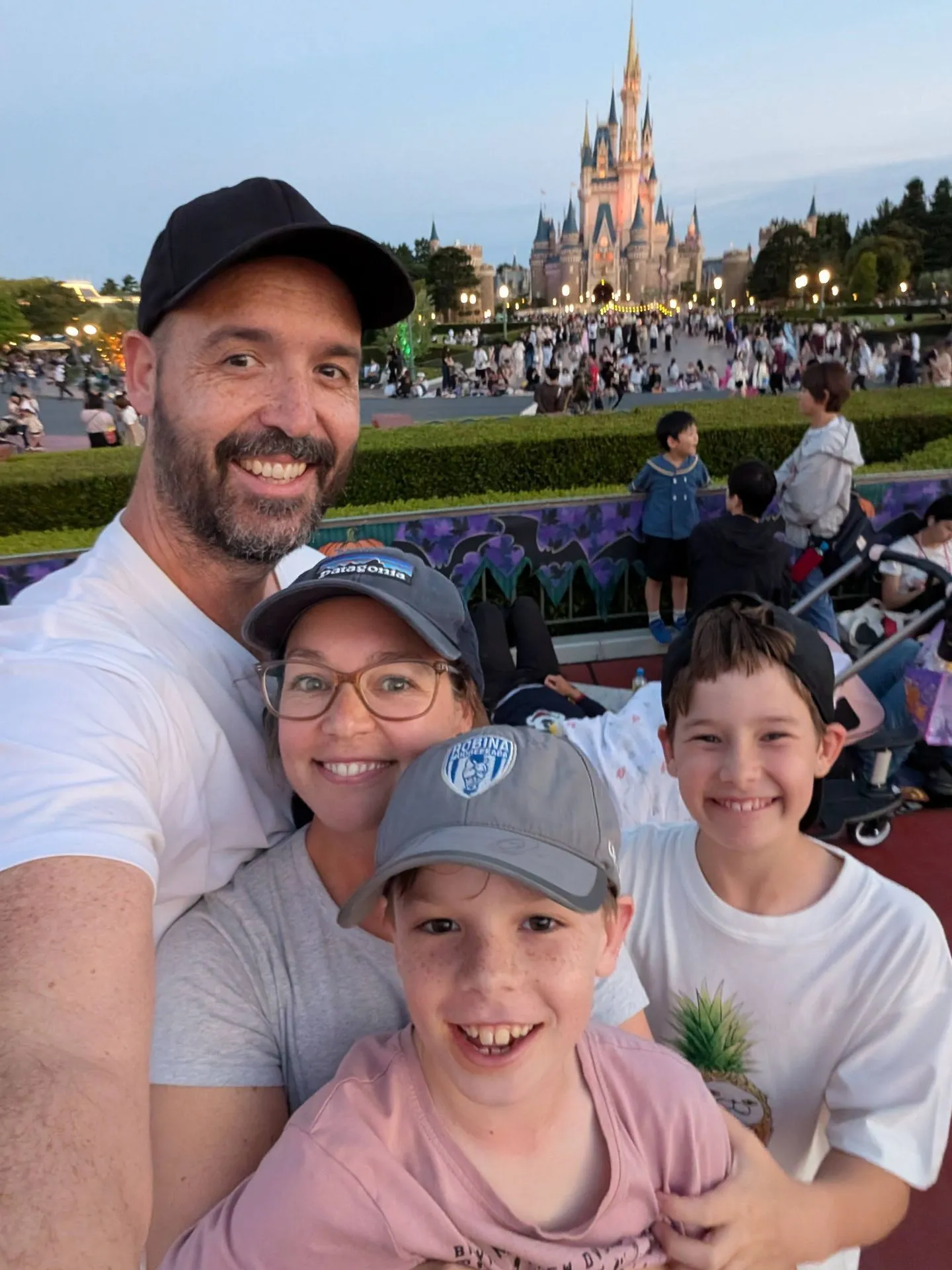 Matt, Lyndsie and the two boys in front of Cinderella's Castle at Tokyo Disneyland at dusk
