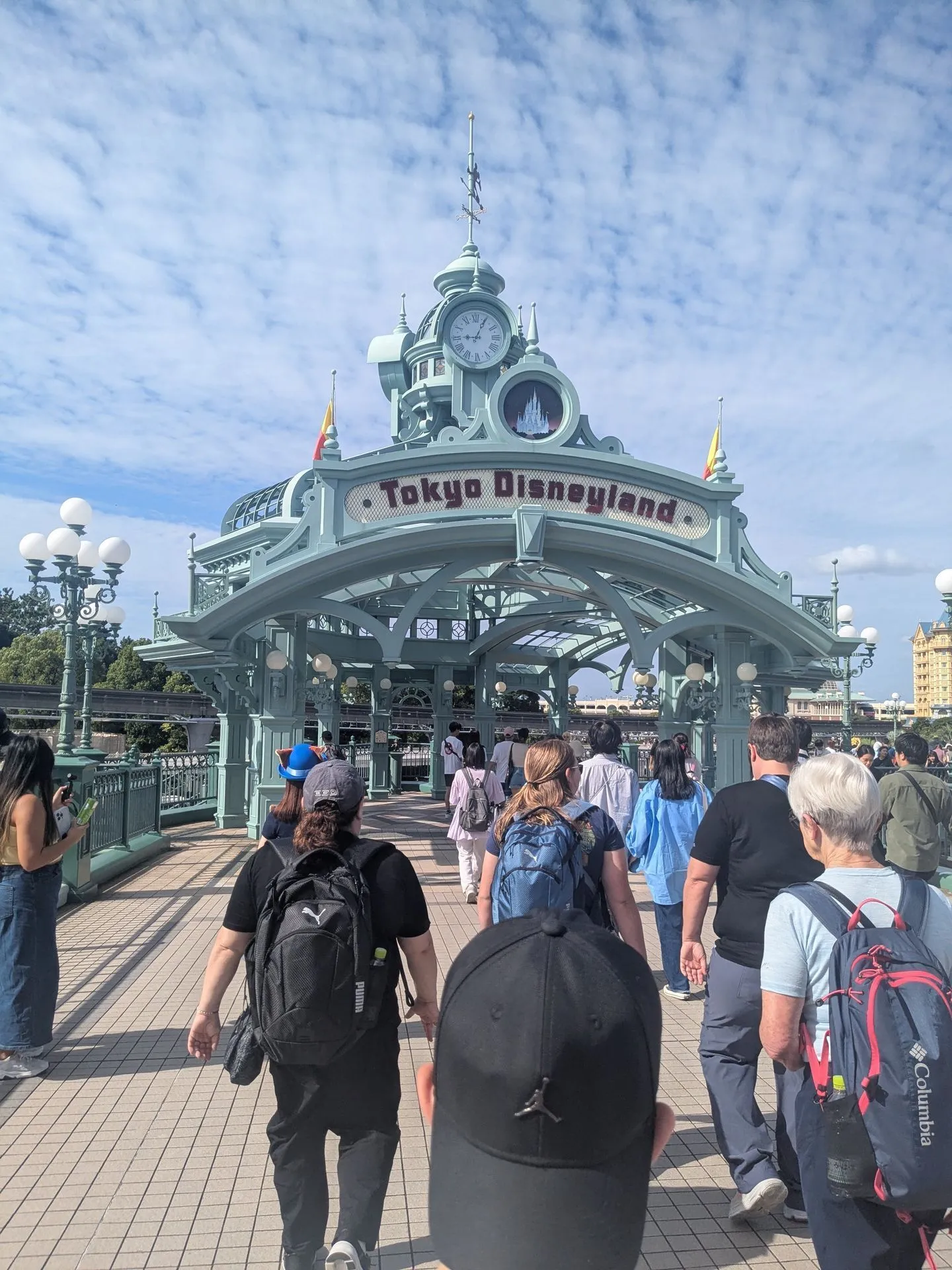 The entrance gate to Tokyo Disneyland with families walking through