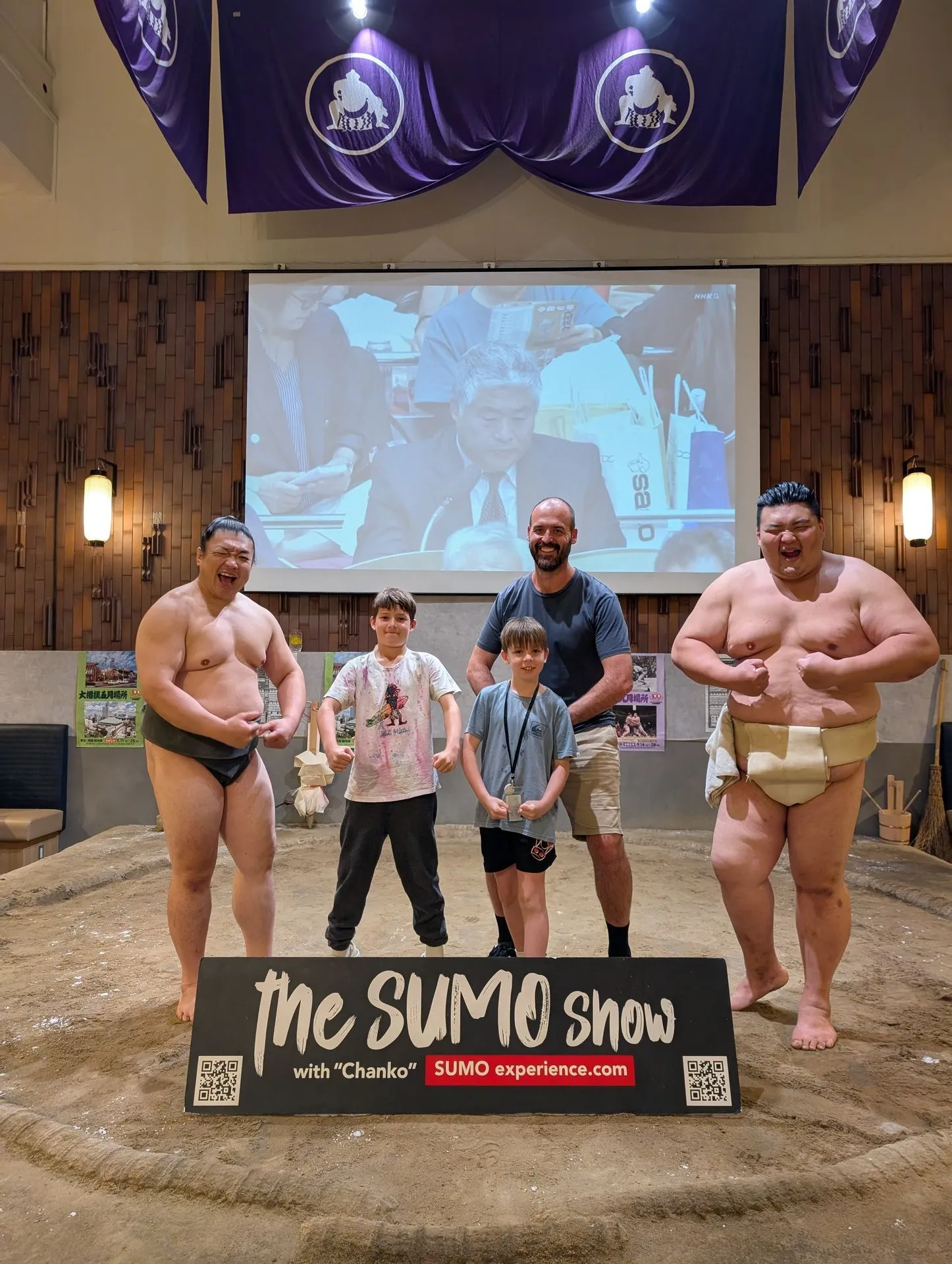 Family on the sumo dohyo with professional wrestlers at a Tokyo sumo show